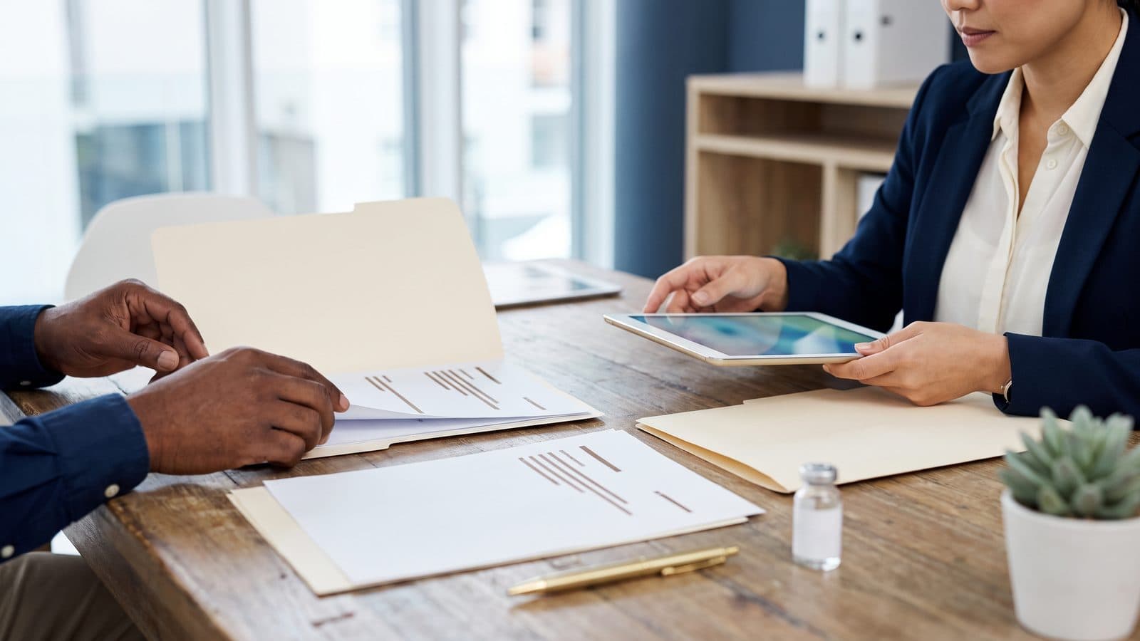 Functional medicine practitioner reviewing a long-form intake with a patient across a wooden desk